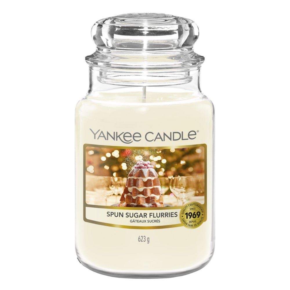 What I Thought of the Yankee Candle Advent House 2014 A tall cylindrical glass jar full of some creamy white wax with a label that has Yankee Candle written in white writing, Spun Sugar Flurries written in black writing, and a picture of a Cake that has some spun sugar on top of it on it, on a white background.