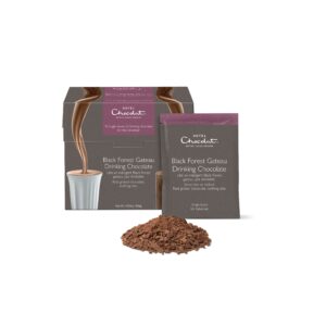 A tall rectangular dark grey cardboard box that has Hotel Chocolat Black Forest Gateaux Hot Chocolate written in bright white writing and a picture of some Hot Chocolate being poured into a short cylindrical cup on it next to a pile of some dark brown hot chocolate powder, on a white background.