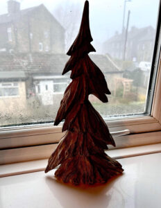 A large triangular bright white and grey resin Christmas Tree on a large rectangular glossy white windowsill.