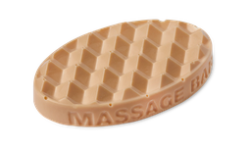 A medium light green oval shaped block of solid massage oil that has a layer of Magnesium Salt Crystals embedded on the top of it, on a white background.