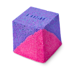 A large light purple cube shaped Bath bomb that has some pieces of Epsom Salt all over it, on a white background.
