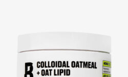 A short cylindrical white plastic tub with a white plastic lid that has By Beauty Bay Colloidal Oatmeal + Oat Lipid written in bold black writing and Rich Moisturiser written in dark purple writing on it, on a white background.
