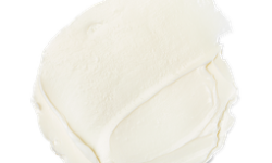 A medium circular puddle of some creamy white moisturiser, on a white background.