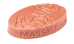 A medium bright pink oval shaped block of solid massage oil that has some petals engraved on it, on a white background.