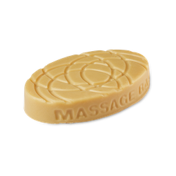 A medium light brown oval shaped block of solid massage oil that has some grooves engraved all over it, on a white background.