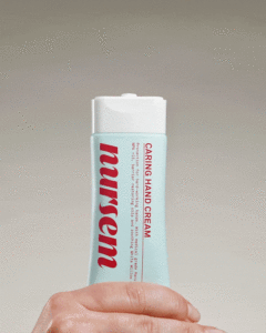 A tall rounded rectangular conical pale blue plastic tube with a white plastic lid that has Nursem Caring Hand Cream written in bright Red writing on it, on a white background.