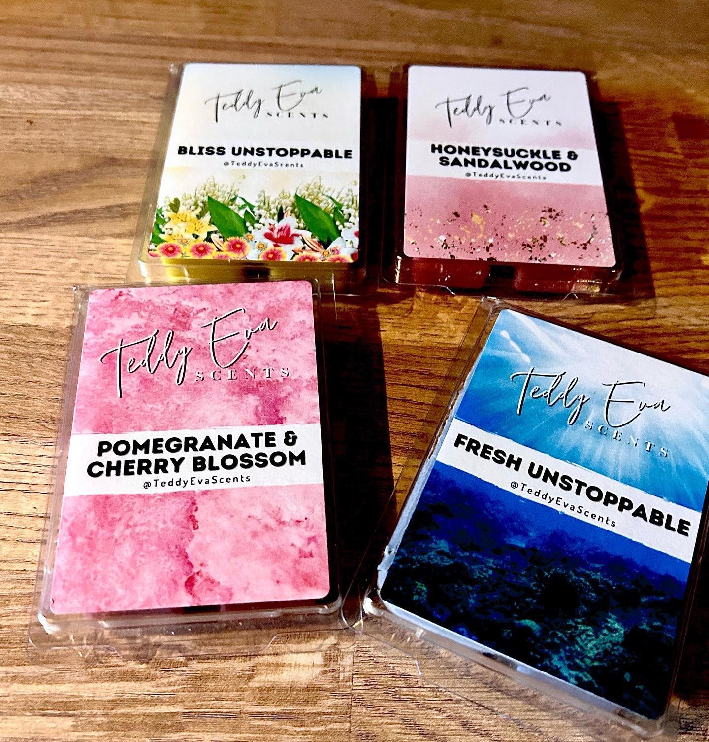 If You Go Down In The Woods Today, You're Sure To Smell Something Nice | Teddy Eva Scents Fresh Start Wax Melt Subscription Box | Gifted A tall rectangular plastic box full of some creamy yellow wax with a white label that has Teddy Eva Scents Bliss Unstoppable Clamshell written in bold black writing on it next to a tall rectangular plastic box full of some creamy blue wax with a white label that has Teddy Eva Scents Fresh Unstoppable Clamshell written in bold black writing on it, a tall rectangular plastic box full of some creamy pink wax with a white label that has Teddy Eva Scents Pomegranate & Cherry Blossom Clamshell written in bold black writing on it, and a tall rectangular plastic box full of some creamy red wax with a white label that has Teddy Eva Scents Sandalwood and Honeysuckle Clamshell written in bold black writing on it, on a white background.