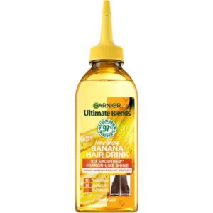 A tall rectangular bright yellow plastic bottle with a bright yellow plastic lid that has Garnier written in bright green writing and Ultimate Blends Hair Drink Nourishing Banana Liquid Conditioner written in bright white writing on it, on a white background.