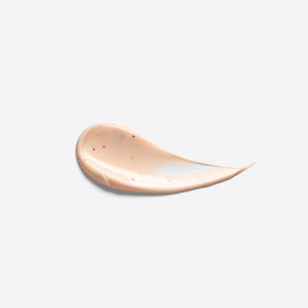 The Origins Of Glowing Skin | Origins Ginseng™ Glow-Boosting Mask A medium circular puddle of some light peachy pink face mask that has some pieces of Red Vitamin C Powder running through it, on a white background.