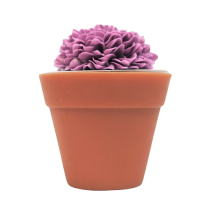 A short cylindrical dark terracotta flower pot shaped block of soap that has some dark purple flowers coming out of the top of it, on a white background.