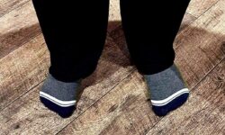 Me wearing a pair of fluffy dark green socks that has Box Menswear written in bold white writing on them stood on a light wooden laminate floor.