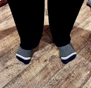 Me wearing a pair of fluffy dark green socks that has Box Menswear written in bold white writing on them stood on a light wooden laminate floor.