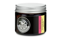 A short cylindrical black glass jar with a silver metallic lid and a gradient black and white label that has Arthur J Hawke Pear Drops Beard Butter written in bold white writing and a picture of a black hawk on it, on a white background.