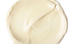 A medium circular puddle of some creamy white body lotion, on a white background.