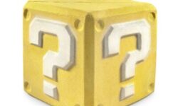 A large golden yellow cube shaped bath bomb that has a bright white question mark engraved on it, on a white background.