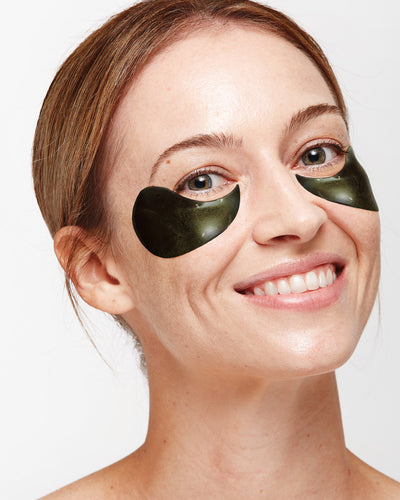 Beauty Isn't Just Skin Deep | Bioglan Beauty Collagen Gummies & Beauty Collagen Effervescent A tall woman with some dark red hair that has a pair of dark green hydrogen eye patches underneath her eyes, on a white background.