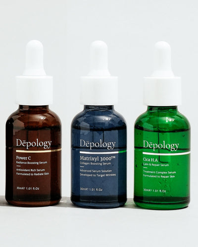 Admirals Always Have The Best Beards | Admiral Grooming Beard Grooming Trio Gift Set A short cylindrical dark blue glass bottle with a white rubber pipette lid that has Depology Matrixyl 3000 Collagen Boosting Serum written in bright white writing on it next to a short cylindrical dark green glass bottle with a rubber pipette lid that has Depology Sica H.A Calm & Repair Serum written in bright white writing on it, and a short cylindrical brown glass bottle with a rubber pipette lid that has Depology Power C Antioxidant Radiance Boosting Serum written in bright white writing on it, on a white background.