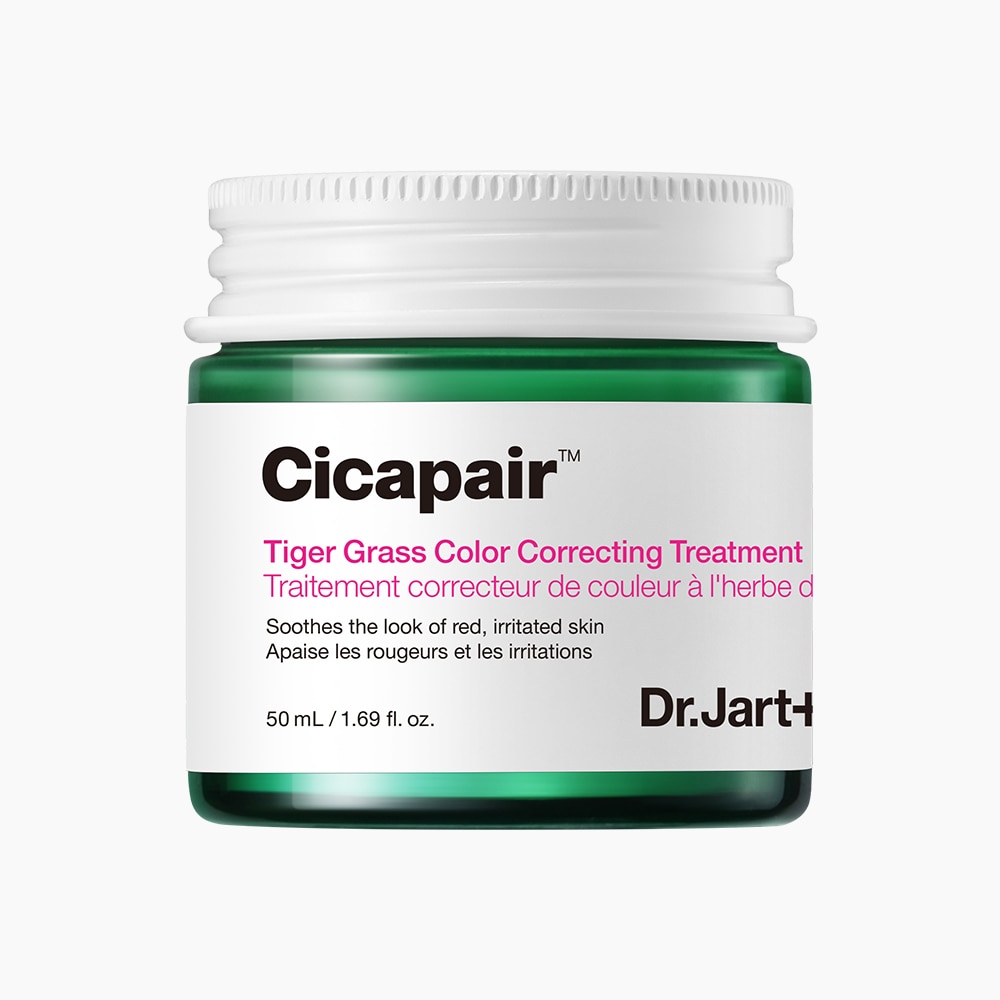 A short cylindrical clear Glass Jar full of some dark green liquid with a white metallic lid and a white label that has Dr. Jart+ written in bold black writing and Cicapair™ Tiger Grass Colour Correcting Treatment written in bright pink writing on it, on a white background.