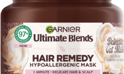 A short cylindrical brown Plastic Tub with a metallic pink Plastic Lid and a metallic pink label that has Garnier Ultimate Blends Delicate Oat Milk Hair Remedy Hypoallergenic Mask written in bold black writing on it, on a white background.