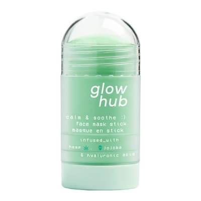 A tall cylindrical clear plastic twist up tube full of some pale green liquid with a light green dial and a bright green label that has Glow Hub Calm & Soothe Face Mask Stick written in bright white writing on it, on a white background.