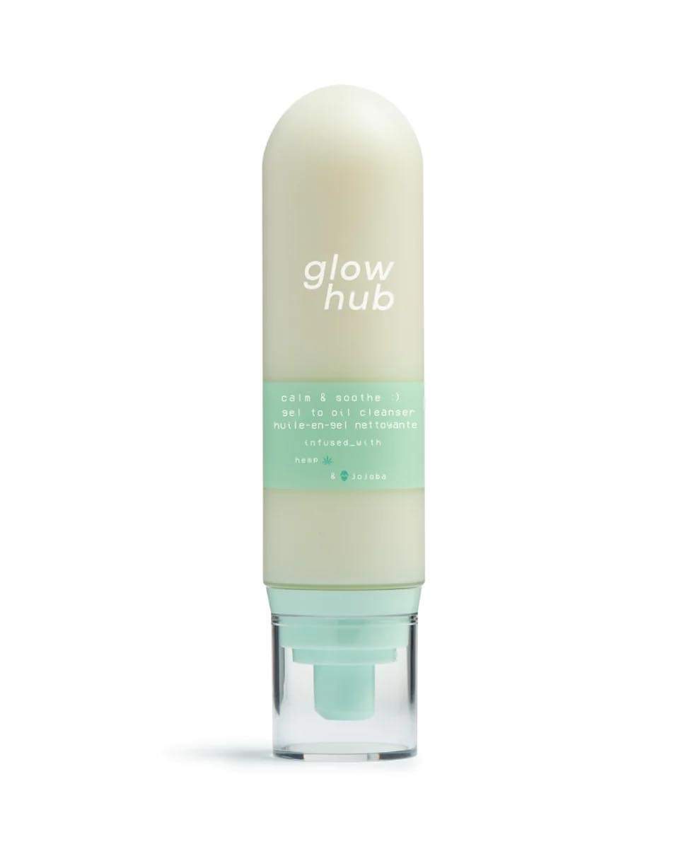 A tall cylindrical dome shaped clear plastic bottle full of some creamy white liquid with a clear plastic lid and a bright green label that has Glow Hub Calm & Soothe Gel To Oil Cleanser written in bright white writing on it, on a white background.