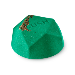 A medium bright blue flat hexagonal shaped bath bomb that has some pieces of Demerara Sugar embedded in it, on a white background.