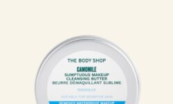 A short cylindrical silver Metal Tin with a gradient bright blue and white label that has The Body Shop Chamomile Sumptuous Makeup Cleansing Butter written in dark green writing on it, on a white background.