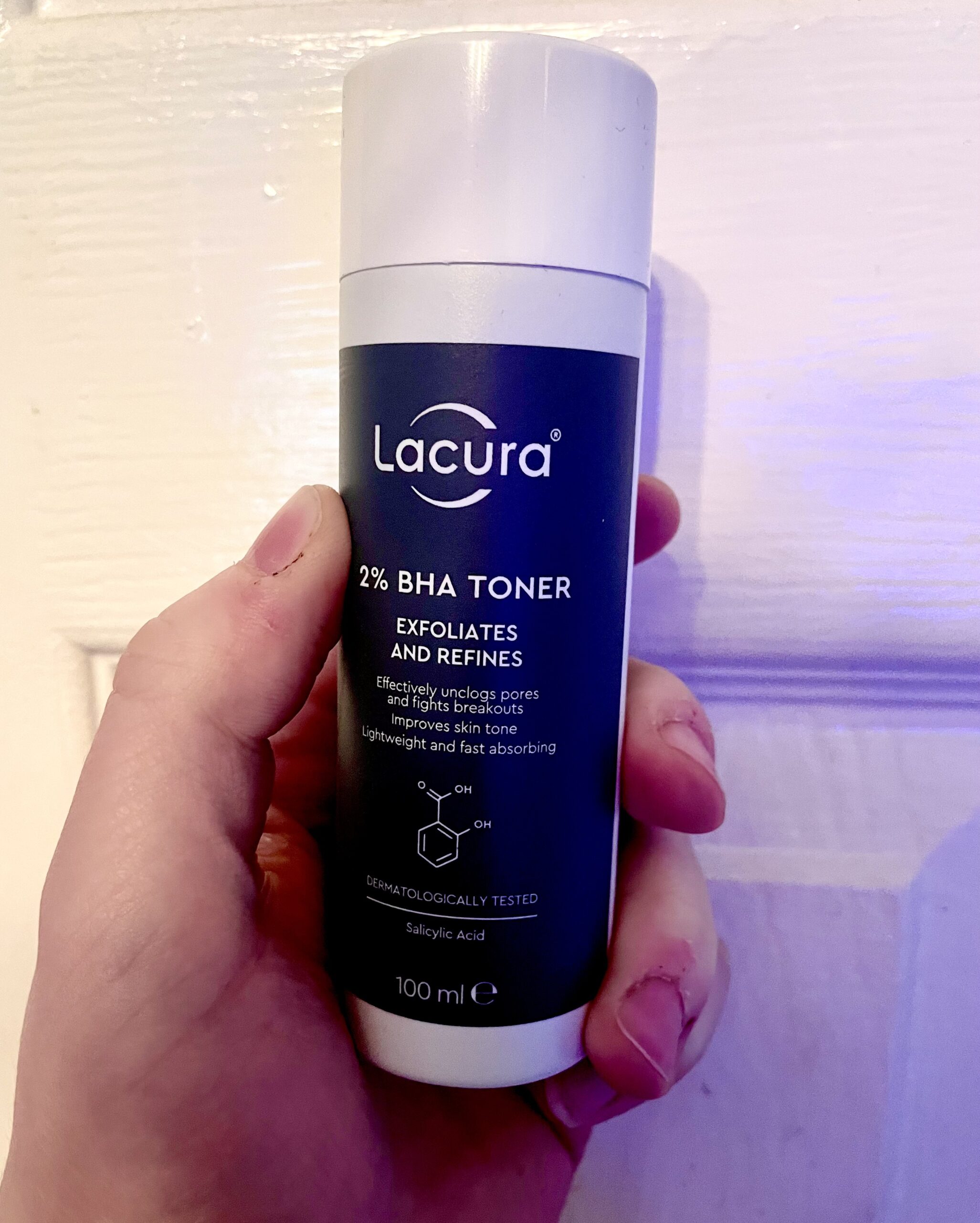 I'm Not Sure I Like That Cashiers' Tone | Aldi Lacura 2% BHA Toner A short cylindrical clear plastic bottle with a black plastic lid and a light blue label that has Aldi Lacura 2% BHA Toner written in bright white writing on it, on a white background.