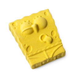 A medium bright yellow rectangular sponge shaped bath bomb that has some large eyes, a sausage nose, and a toothy grin engraved on it, on a white background.