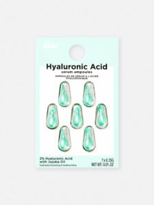 seven small teardrop shaped plastic ampoules full of some clear liquid encased in some clear plastic on a medium rectangular piece of white cardboard that has Primark PS… Skin + Hyaluronic Acid Serum Ampoules written in bold black writing on it, on a white background.