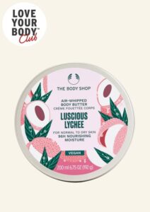A short cylindrical bright white plastic tub with a bright white plastic lid and a bright pink label that has The Body Shop Luscious Lychee Air-Whipped Body Butter written in dark green writing and a picture of some bright pink slices of Lychee on it, on a white background.