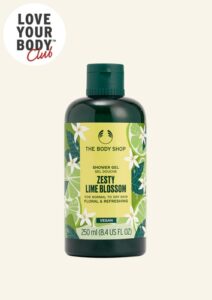 A tall cylindrical dark green plastic Bottle with a dark green plastic lid and a bright yellow label that has The Body Shop Zesty Lime Blossom Shower Gel written in dark green writing, some pictures of some dark green slices of lime and some pictures of some bright white lime blossoms on it, on a white background.