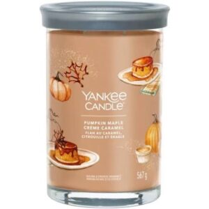 A tall cylindrical glass jar full of some pale brown wax with a label that has Yankee Candle written in white writing, Pumpkin Maple Creme Caramel written in white writing, and a picture of some slices of some golden brown pumpkin pie on it, on a white background..