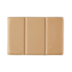 A medium creamy beige rectangular chocolate bar shaped block of solid sun cream oil, on a white background.