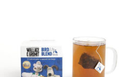 A large square dark blue cardboard box with a creamy white label that has Bird & Blend Tea Company More Tea Gromit? Tea written in bold black writing, Wallace & Gromit written in bold black writing, and a picture of a large dark blue square teabag on it, on a white background.