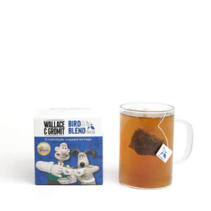 A large square dark blue cardboard box with a creamy white label that has Bird & Blend Tea Company More Tea Gromit? Tea written in bold black writing, Wallace & Gromit written in bold black writing, and a picture of a large dark blue square teabag on it, on a white background.