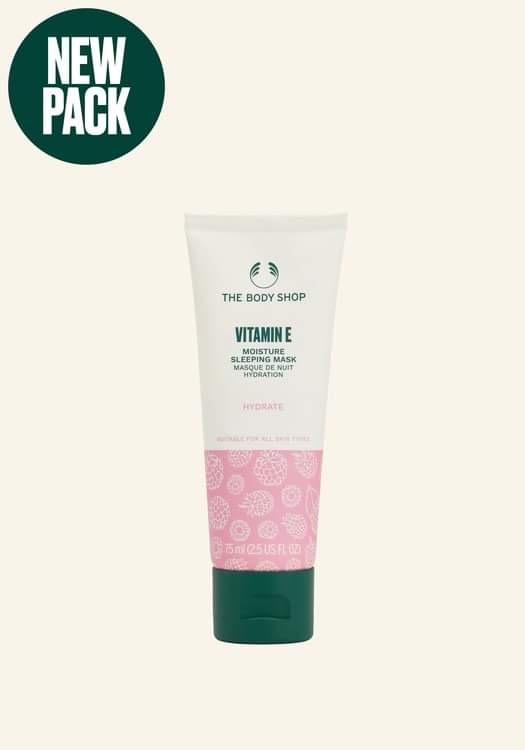 A tall conical gradient bright pink and white plastic tube with a dark green plastic lid that has The Body Shop Vitamin E Moisture Sleeping Mask written in dark green writing on it, on a white background.
