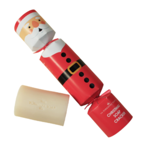 A medium rectangular bright red and white cracker shaped block of Soap that has a Santa’s Face with a White Beard and a black belt with a bright gold buckle Engraved on it, on a white background.