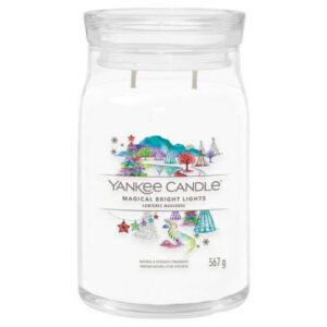 A tall cylindrical glass jar full of some creamy white wax with a label that has Yankee Candle written in white writing, Magical Bright Lights written in black writing, and a picture of a dark blue sky full of some bright white stars and clouds and a multicoloured rainbow on it, on a white background.