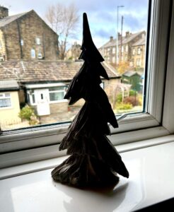 A large triangular bright white and grey resin Christmas Tree on a large rectangular glossy white windowsill.