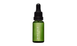 A short cylindrical dark green glass bottle with a brown rubber pipette lid and a black label that has Disciple Dreamy Skin Retinyl Oil written in bright white writing on it, on a white background.
