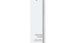 A tall rectangular bright white cardboard box that has Dr. Hauschka Cleansing Cream written in bold black writing on it and a picture of a bright yellow stripe on it, on a white background.