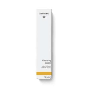 A tall rectangular bright white cardboard box that has Dr. Hauschka Cleansing Cream written in bold black writing on it and a picture of a bright yellow stripe on it, on a white background.
