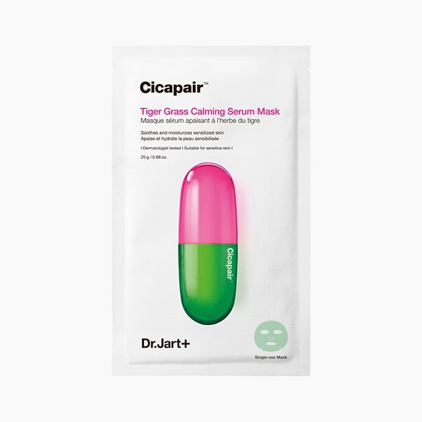 A tall rectangular bright white paper pouch that has Dr. Jart+ Cicapair™ Tiger Grass Calming Serum Mask written in bold black writing and a picture of a gradient bright pink and green capsule on it, on a white background.