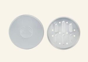 A medium circular silver metal Shampoo Bar Case next to a small circular silver metal drip tray that has some grooves and holes all over it, on a white background.