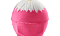 A medium bright Pink hexagonal spherical shaped Bath Bomb that has a bright white flower engraved on it, on a white background.
