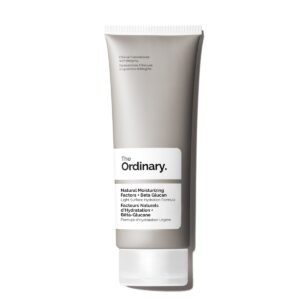 A tall flat conical bright silver plastic tube with a black plastic lid that has The Ordinary Natural Moisturising Factors + Beta Glucan written in bold black writing on it, on a white background.