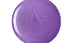 A medium circular puddle of some bright purple shower gel that has some pieces of silver lustre running through it, on a white background.