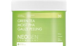A short cylindrical gradient bright green and dark green plastic tub with a white plastic lid that has Neogen Dermalogy Green Tea Moist PHA Gauze Peeling Pads written in bright white writing on it, on a white background.