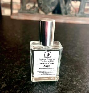 A short square glass bottle full of some clear liquid with a silver metal lid and a white label that has The Perfume People The Quirky Line Time And Time Again Eau De Parfum Spray written in bold black writing on it, on a white background.
